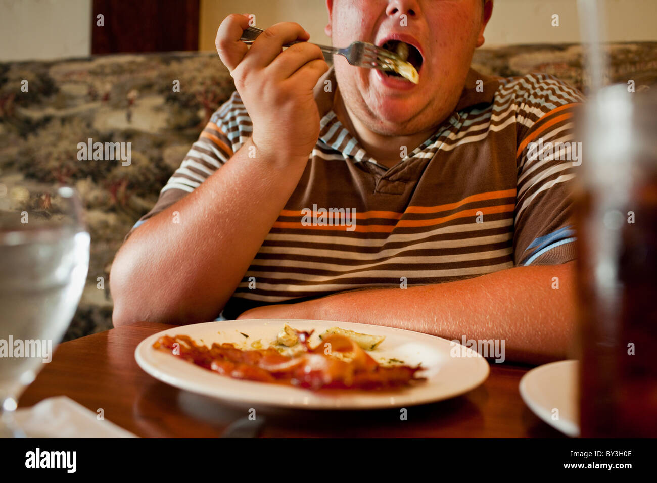 La Grange, California, United States.  A teenager takes a bite of pasta for lunch, with a side of bacon. Stock Photo