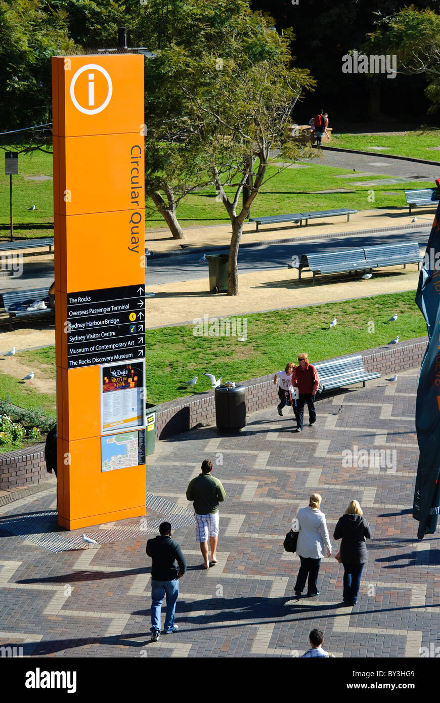 Tourists walk past a large orange informative sign at Circular Quay, one of Sydney's most popular tourist areas Stock Photo