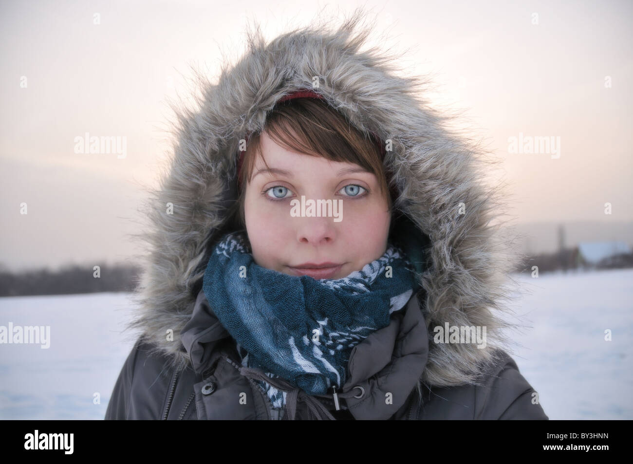 Woman with blue eyes wearing a hooded parka  in snow Stock Photo