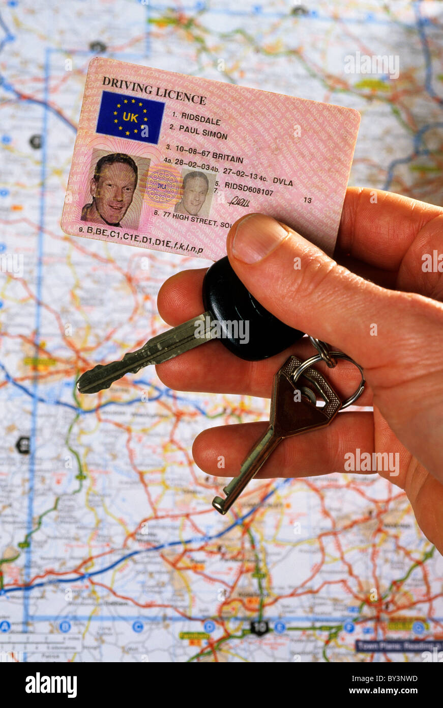 driver holding uk driving licence in front of travel map Stock Photo