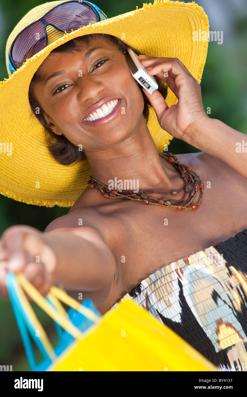 Beautiful and Fashionable African American woman with colorful shopping bags, smiling and talking on her cell phone Stock Photo
