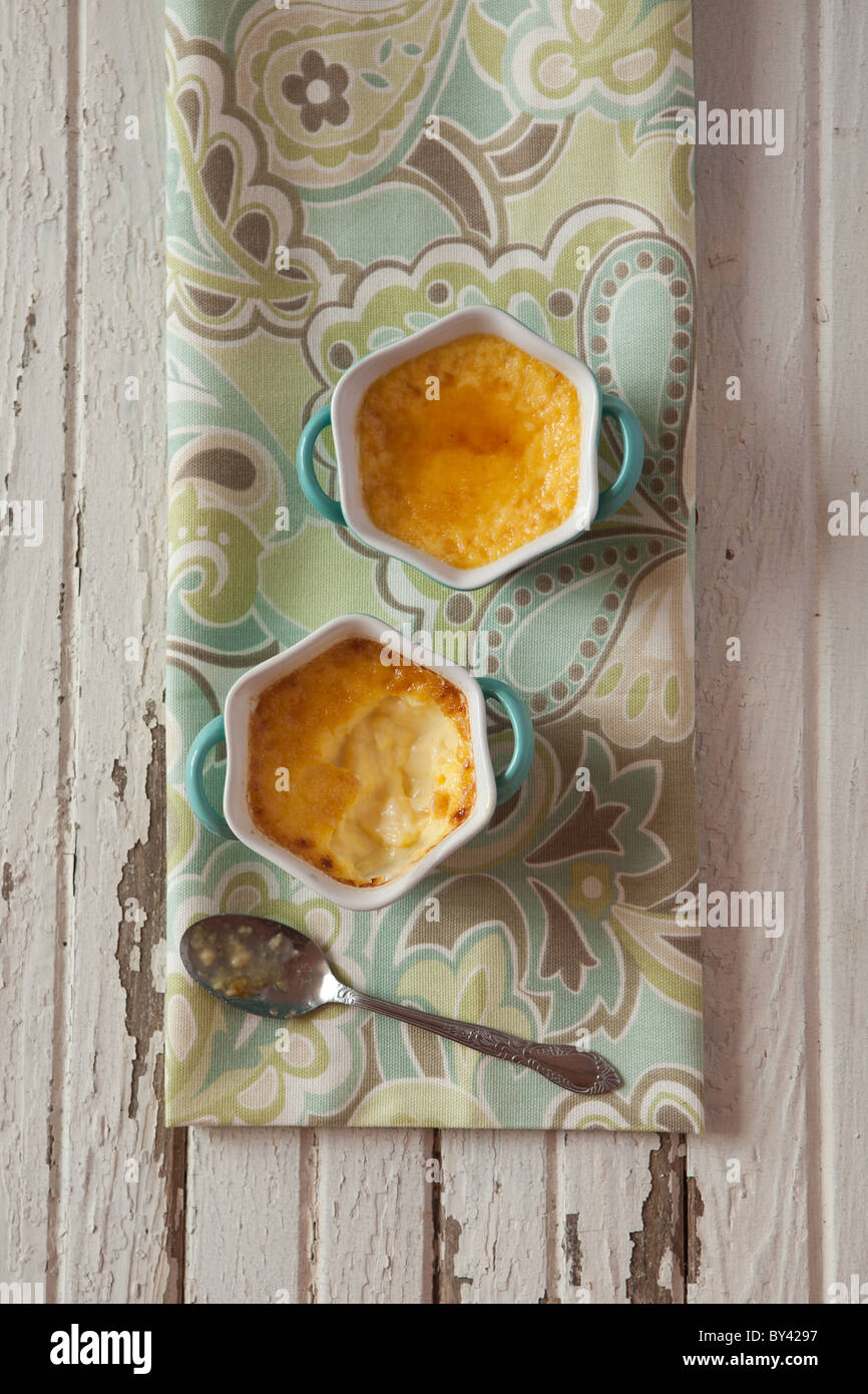 Creme brulee in blue ramekins on a rustic white surface Stock Photo