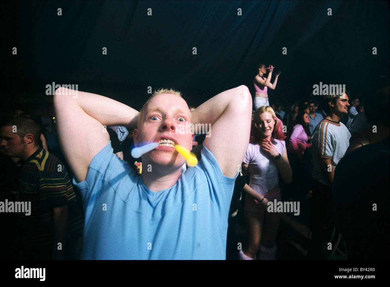 Man in night club holding glow sticks in his mouth. Stock Photo