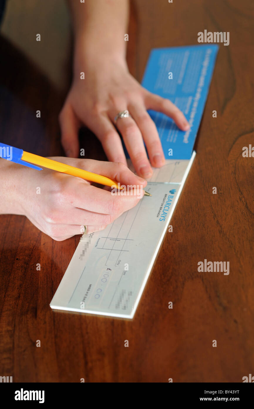 Young woman writing a cheque using chequebook UK Stock Photo Alamy