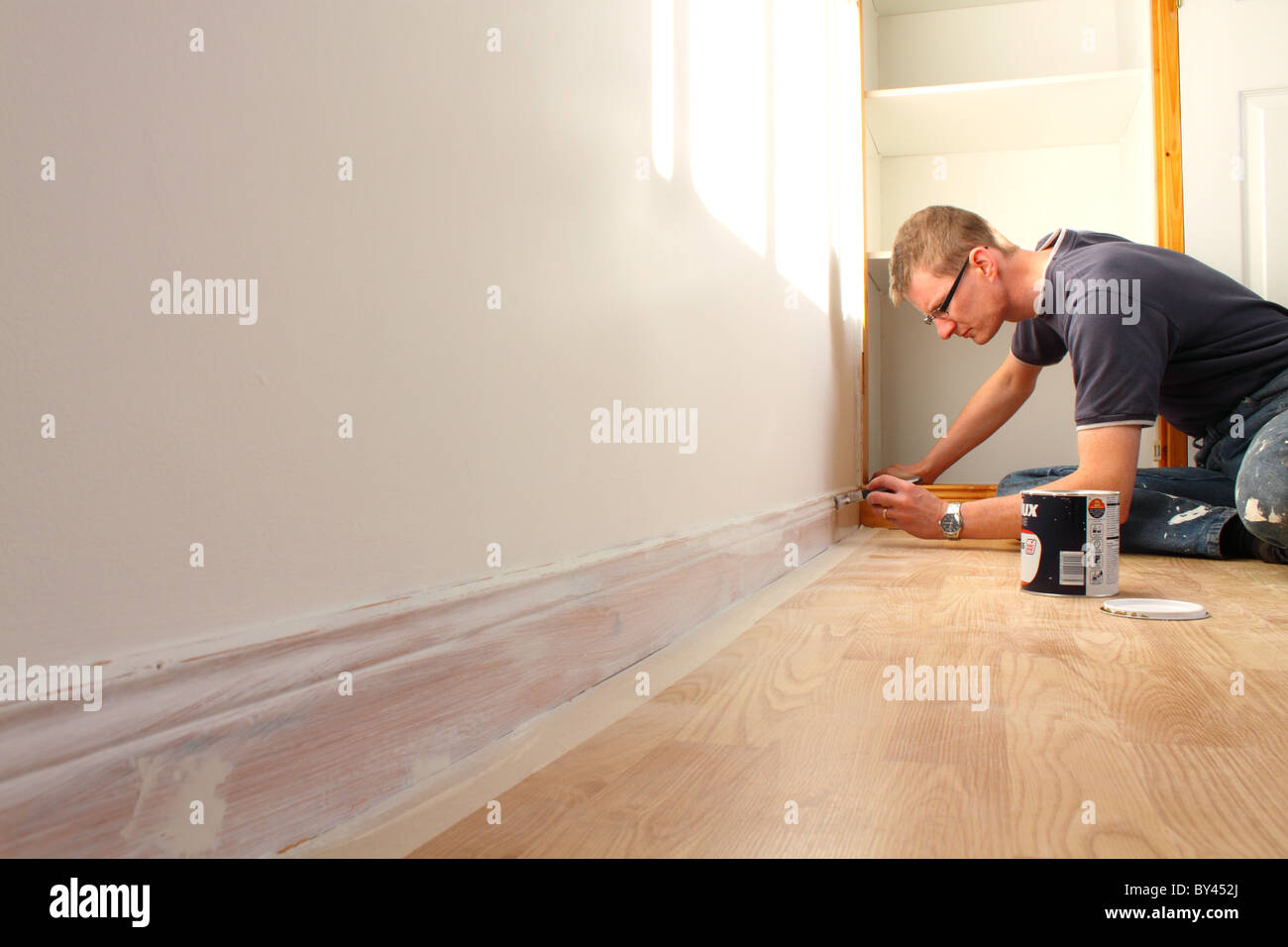 Man painting skirting board in a UK home Stock Photo