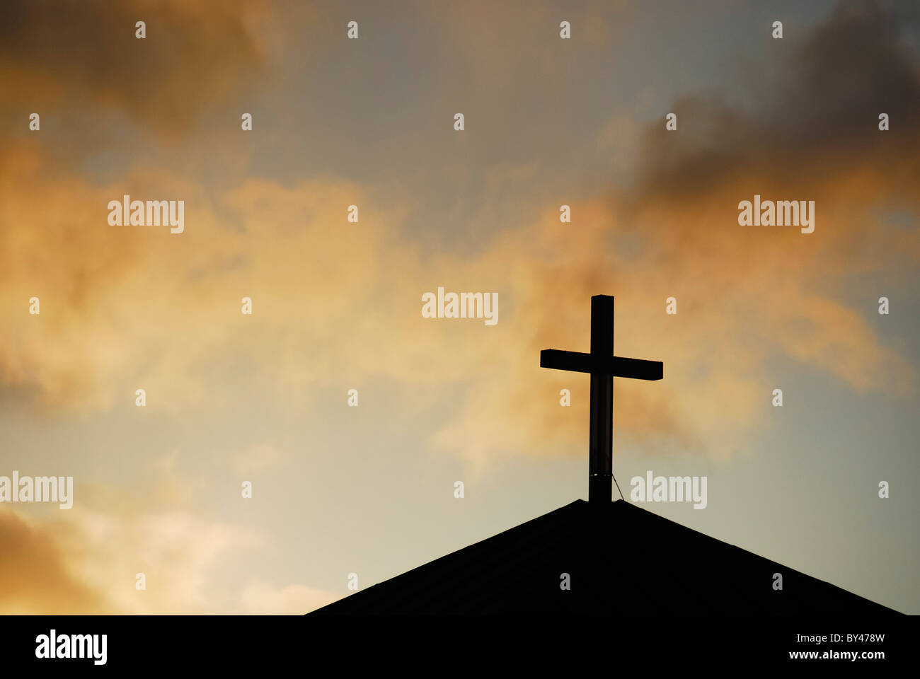 Silhouetted church cross against a dramatic cloudy sky Stock Photo