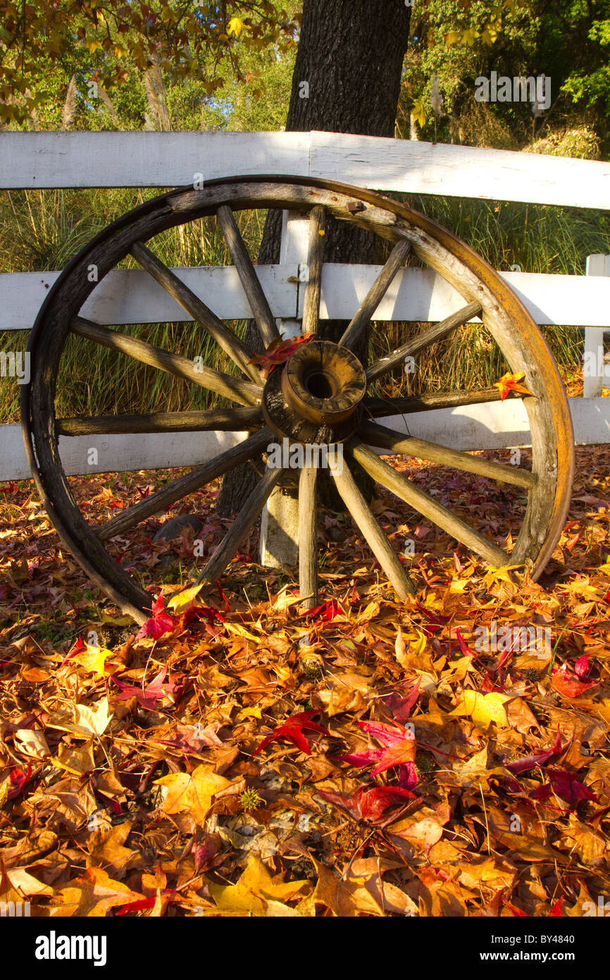 A Wagon Wheel rests on a rural fence with fall colors Stock Photo - Alamy