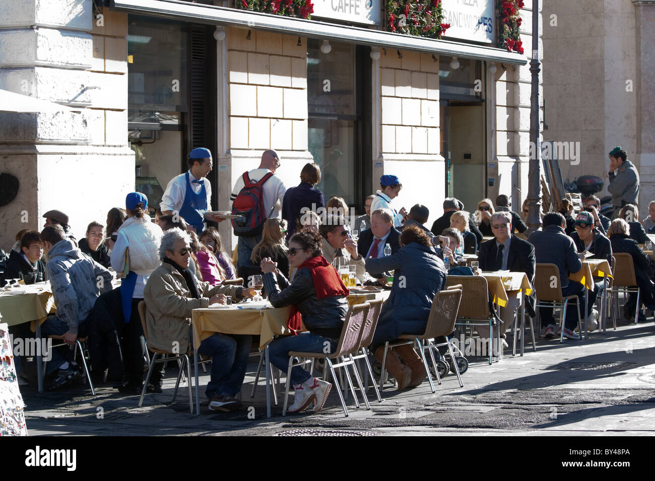 people tourists sitting at touristic cafeteria bar in the street in a winter sunny day Rome Italy Stock Photo
