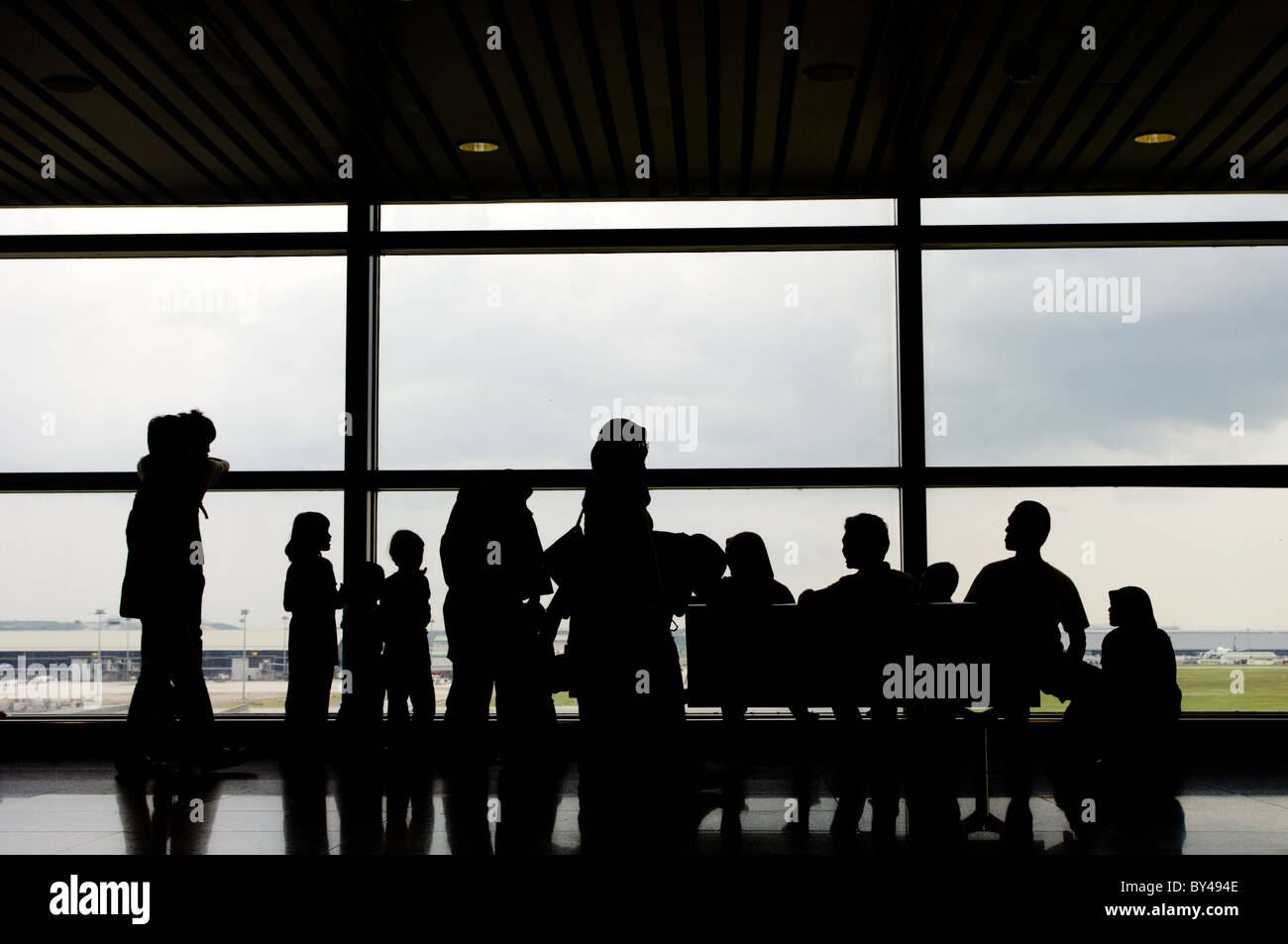 silhouettes of family as viewing through glass panel of airport Stock Photo