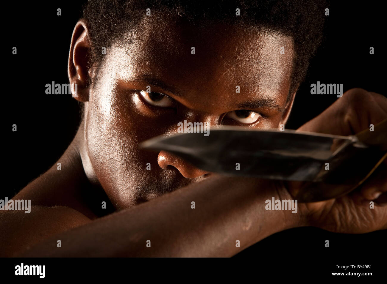 Young black male model posing with a knife