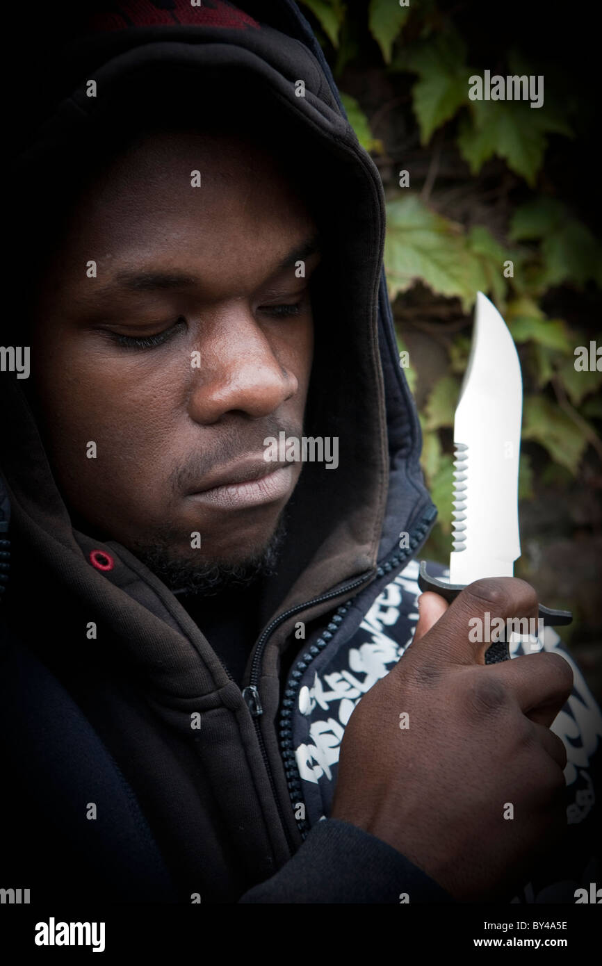 Young black youth model wearing a hoody holding a knife Stock Photo