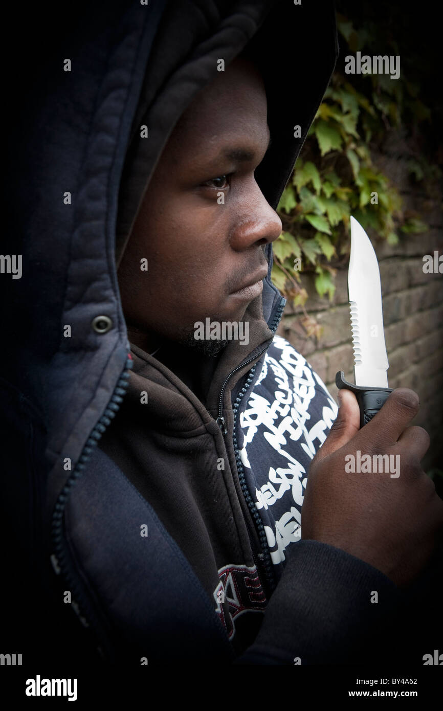 Young black youth model wearing a hoody holding a knife Stock Photo