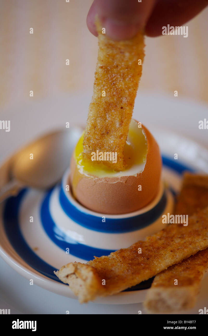 Boiled egg in egg cup with tea spoon and buttered soldiers Stock Photo