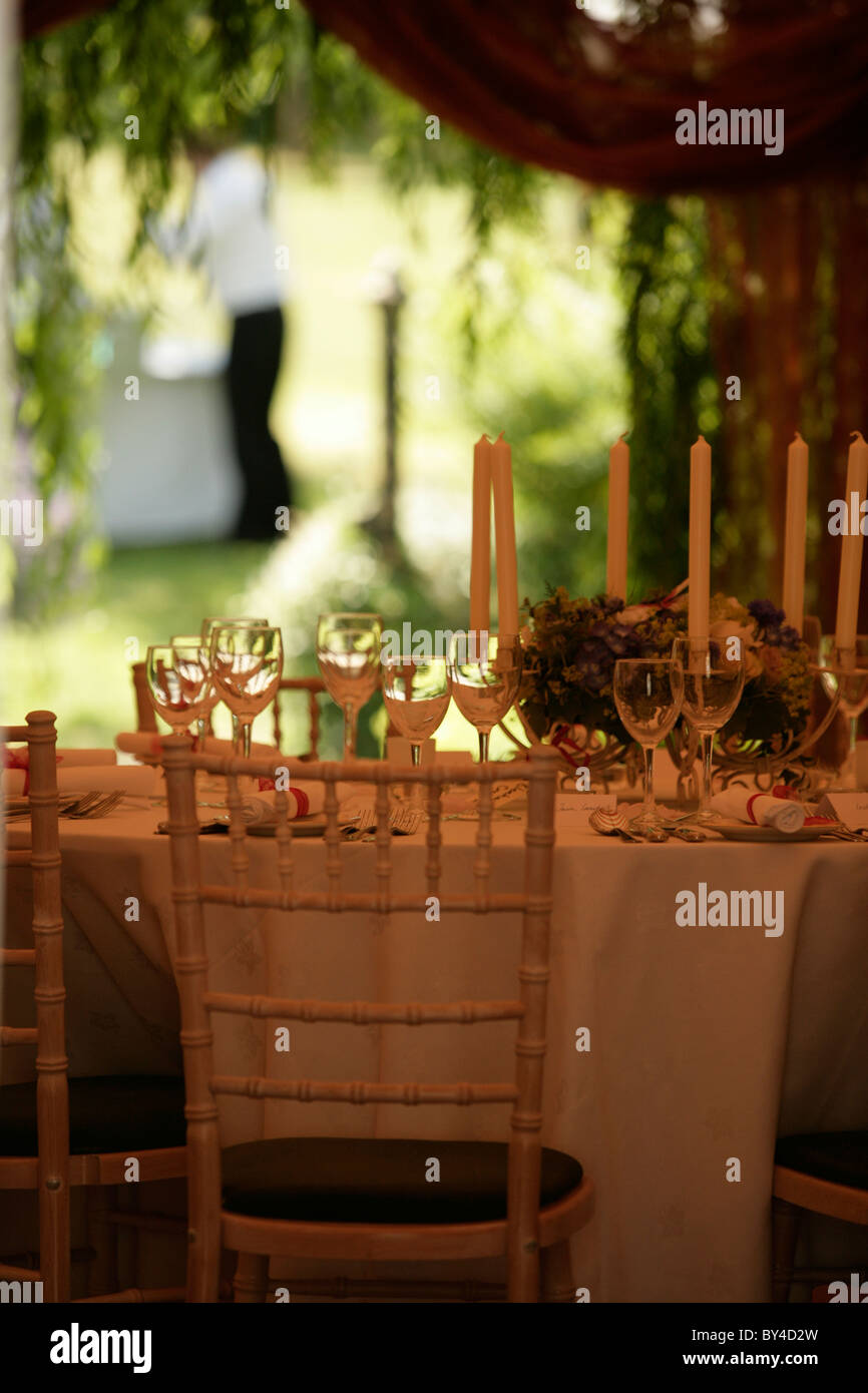 Table laid for party in marquee with glasses and candles. Stock Photo