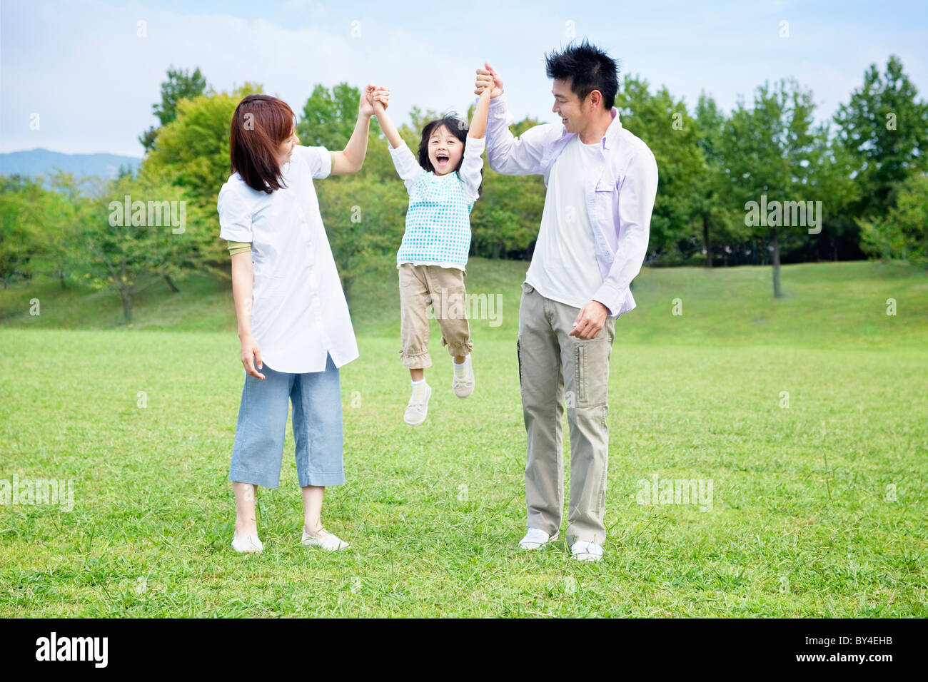 Parents swinging daughter Stock Photo