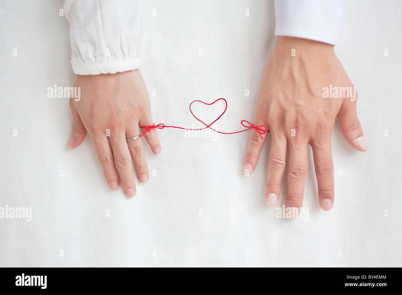 String on woman and man's pinkies tying them together Stock Photo