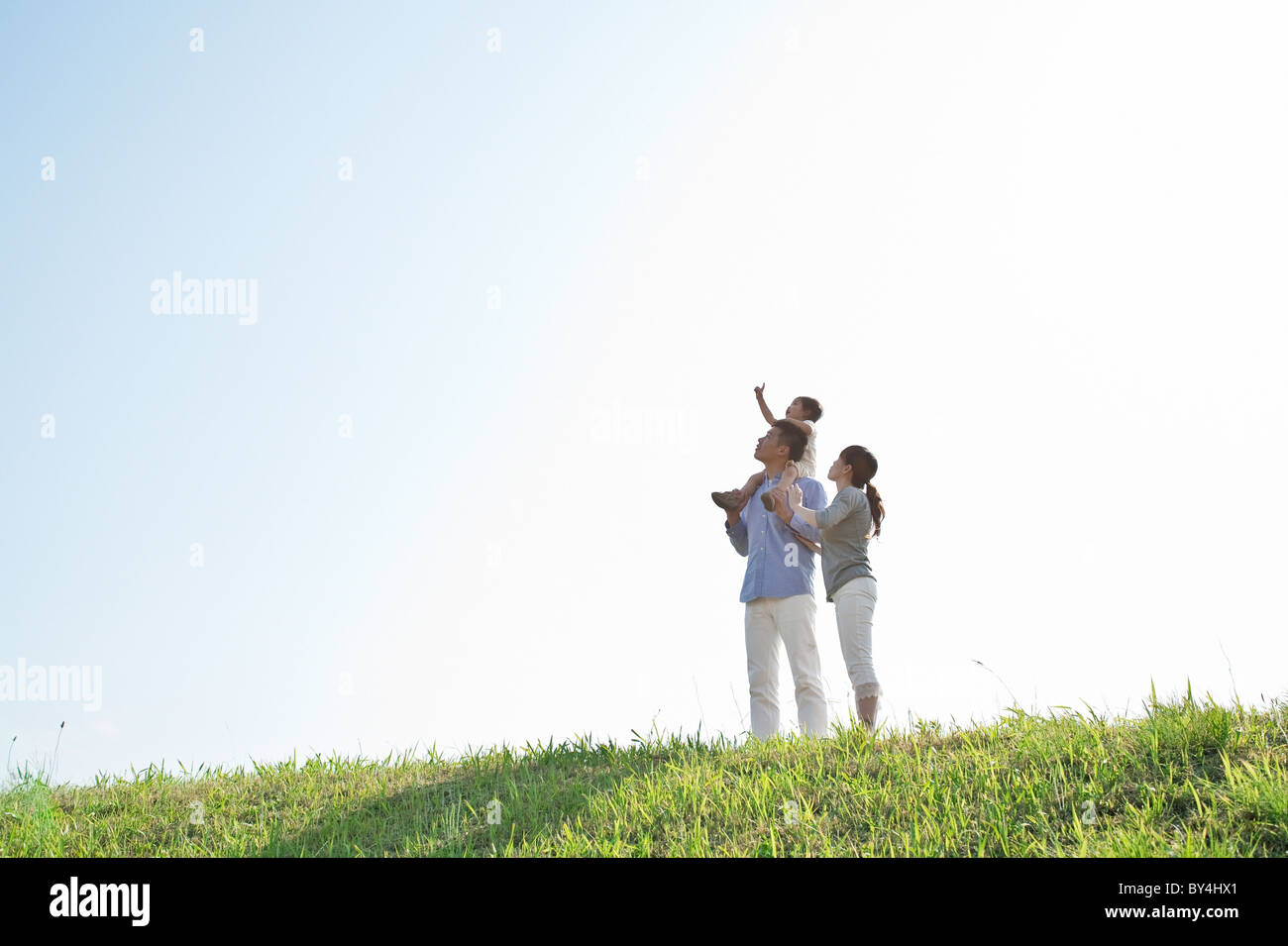 Father carrying daughter on shoulder looking up Stock Photo