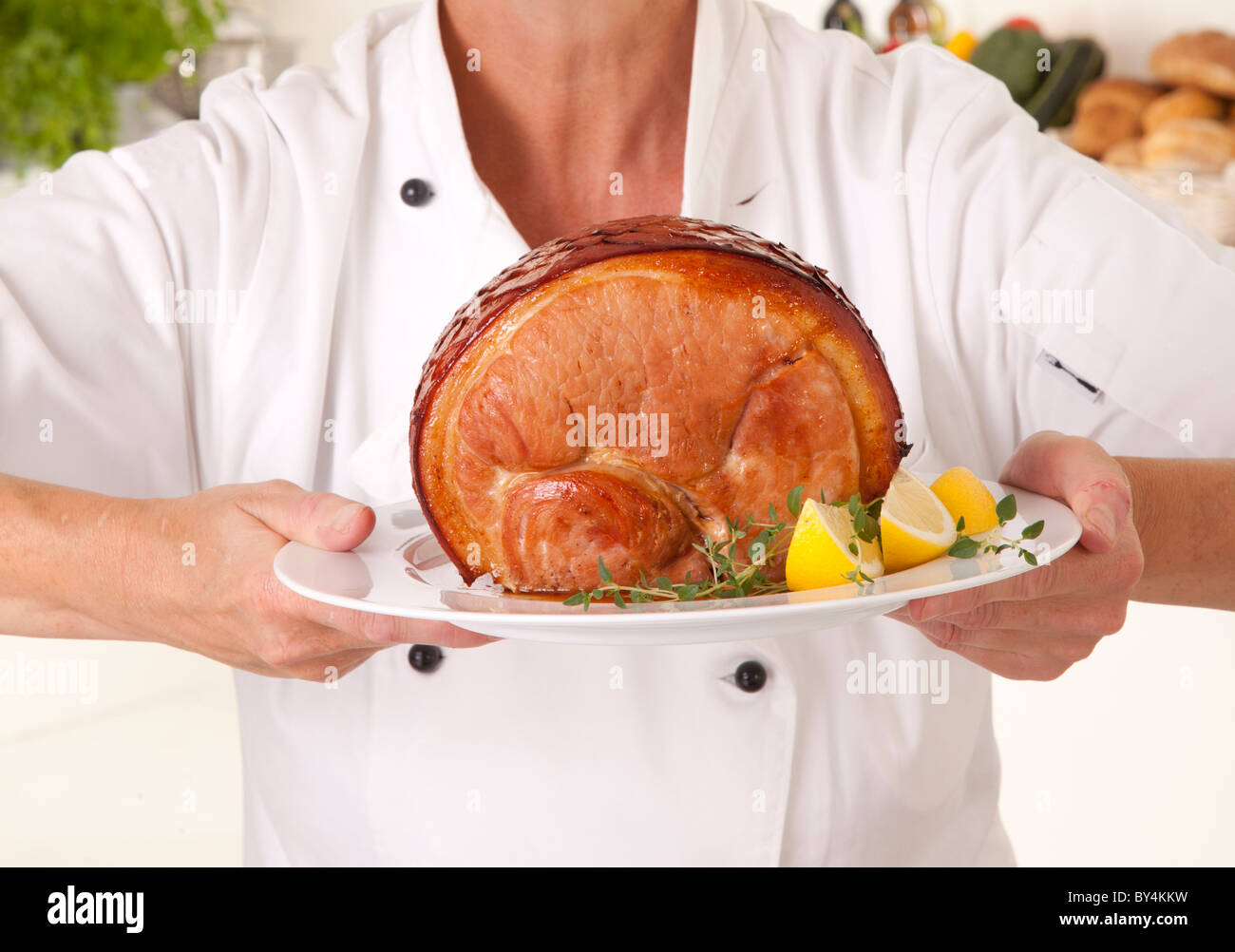 CHEF HOLDING PLATE WITH COOKED GAMMON Stock Photo