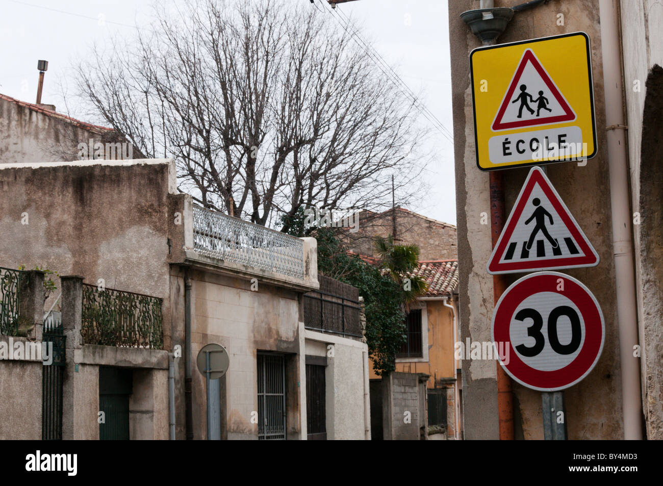 Road signs warning of a 30 kph speed limit, a pedestrian crossing and a School in a French village. Stock Photo