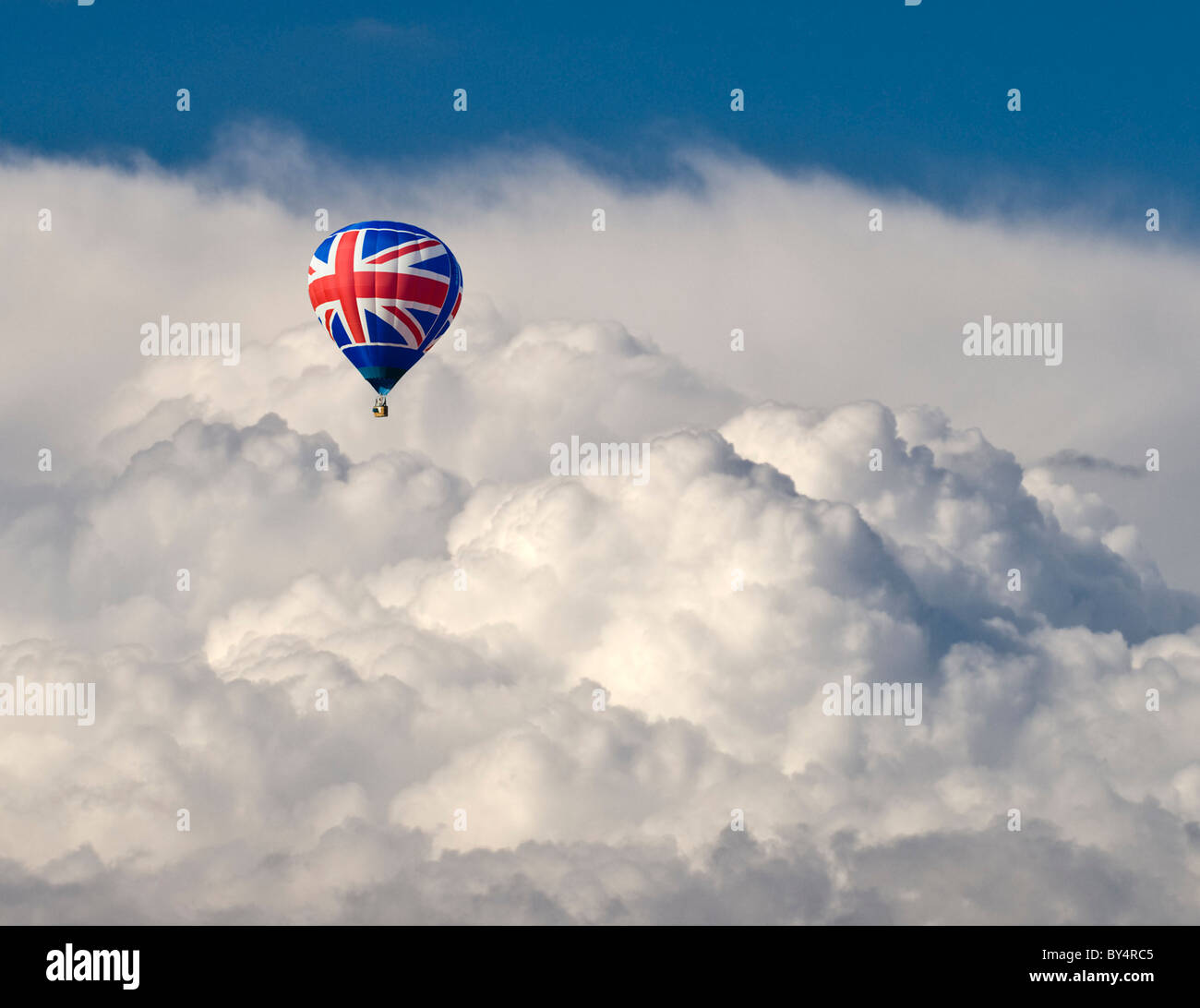 A hot air Balloon with a Union flag motif flying in isolation in front of dramatic storm clouds Stock Photo