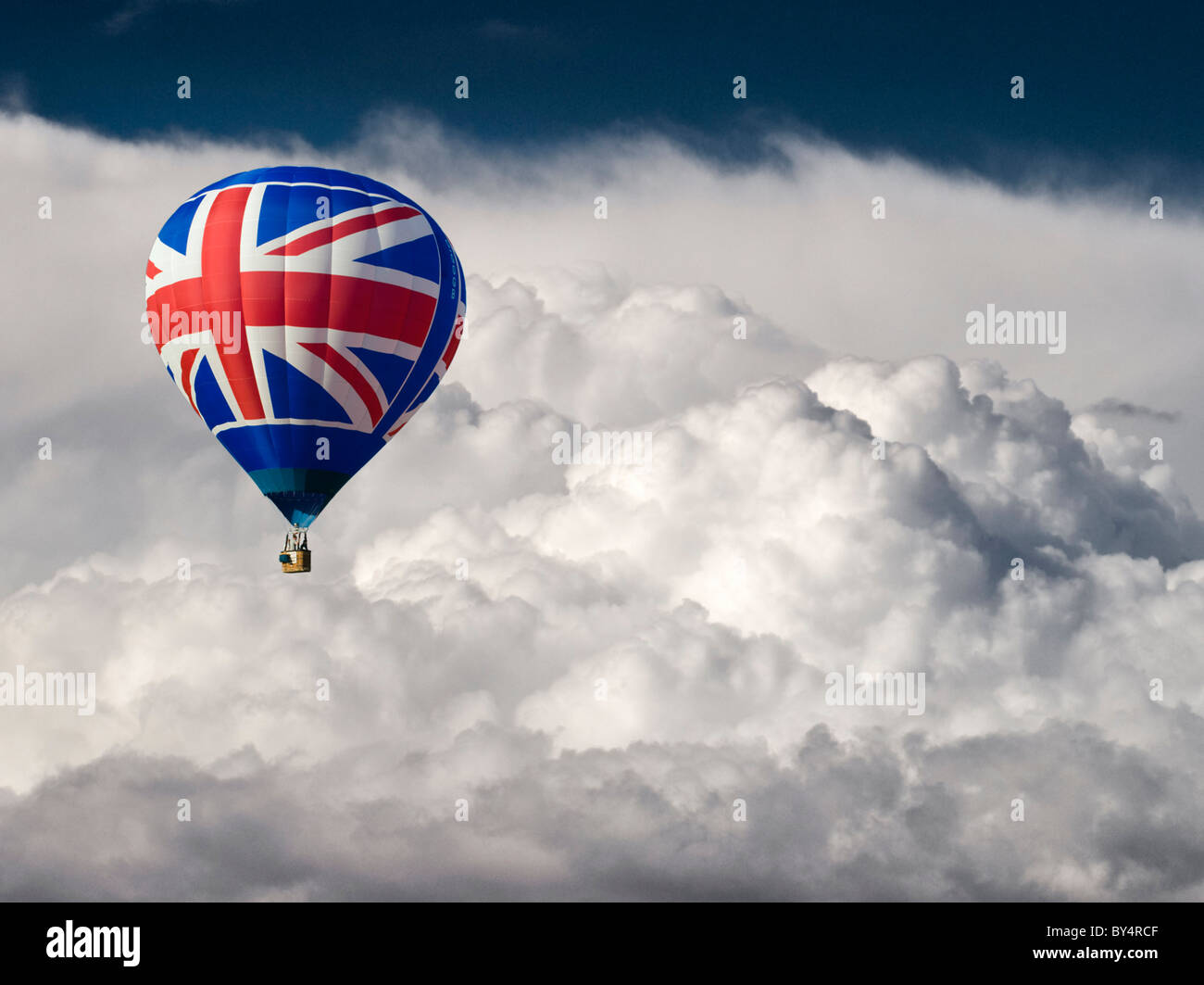 A hot air Balloon with a Union flag motif flying in front of dramatic storm clouds Stock Photo