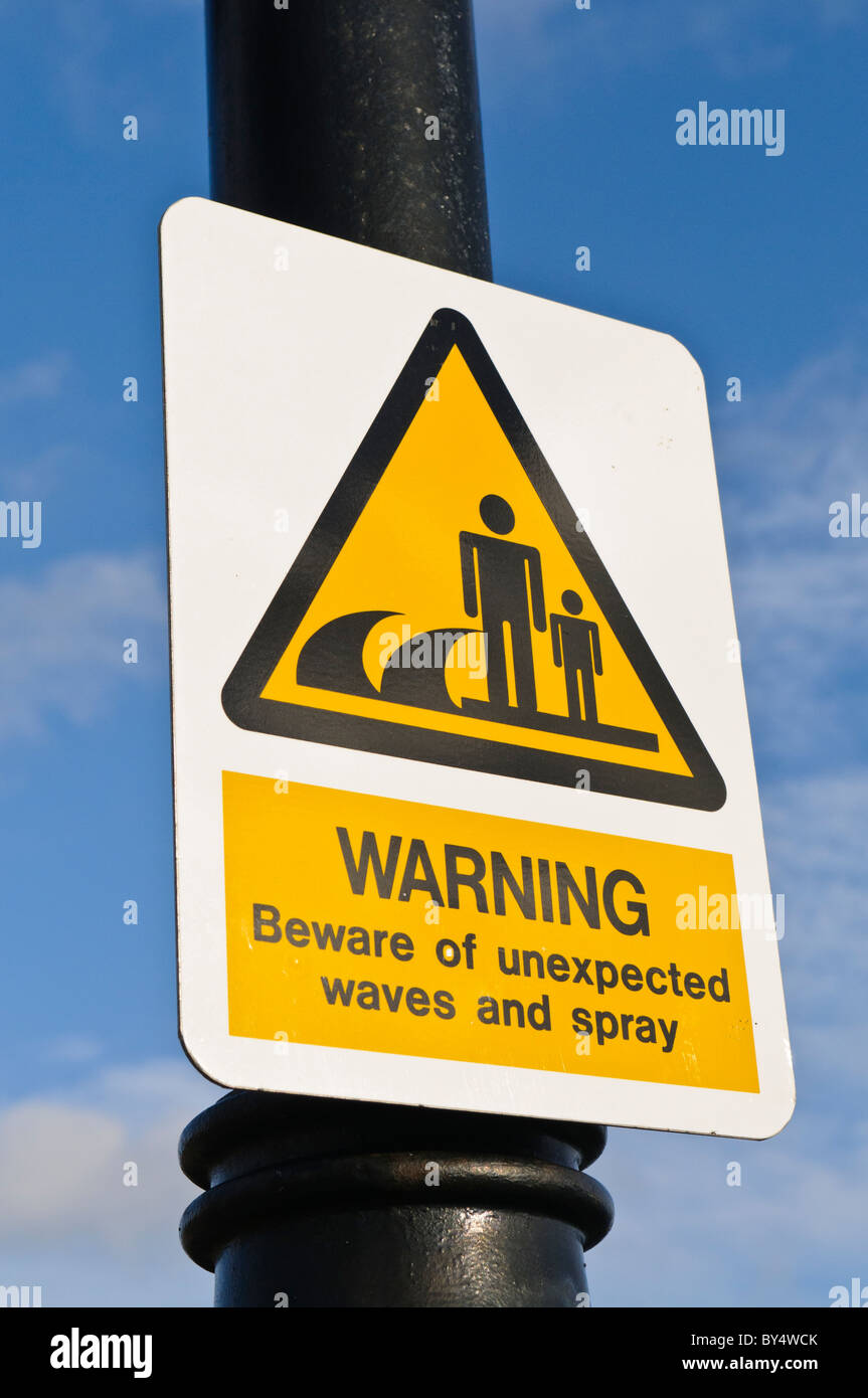 Sign warning public about unexpected waves and spray Stock Photo