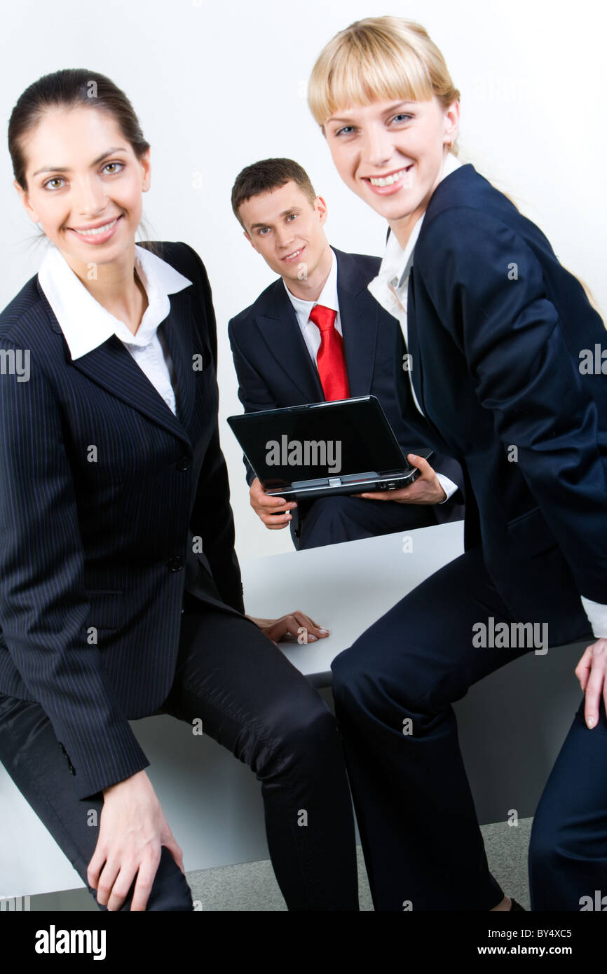 Image of smiling business women sitting on the table in front Stock Photo