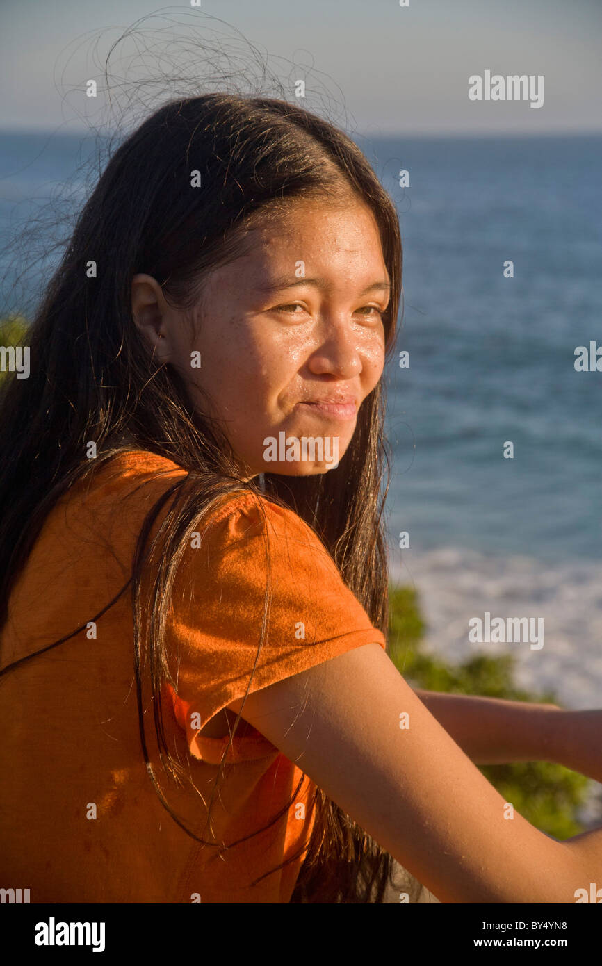 A 15-year-old Asian-American teen grimaces in bright afternoon sunlight in Laguna Beach, California. MODEL RELEASE Stock Photo