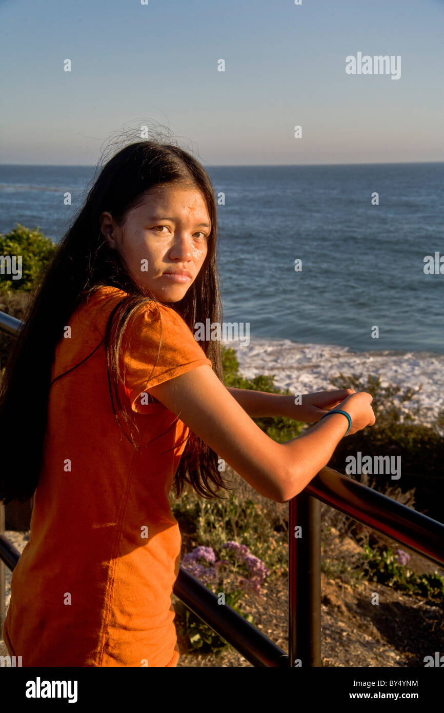 A 15-year-old Asian-American teen stares over her shoulder in bright afternoon sunlight in Laguna Beach, California. MODEL RELEA Stock Photo