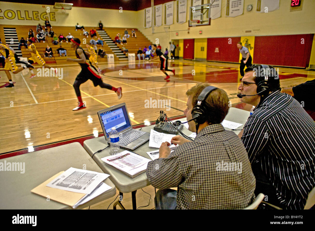 A campus radio announcer (right) provides a running commentary on a basketball game in the college gymnasium . Stock Photo