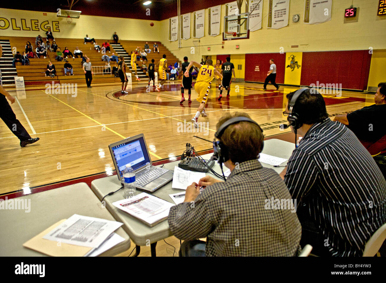 A campus radio announcer (right) provides a running commentary on a basketball game in the college gymnasium . Stock Photo