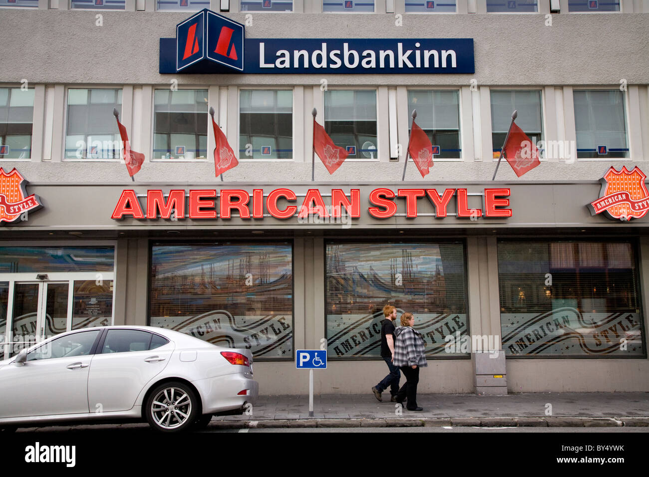 People walking past 'Landsbanki Islands' bank headquarters and 'American Style' hamburger restaurant. Stock Photo