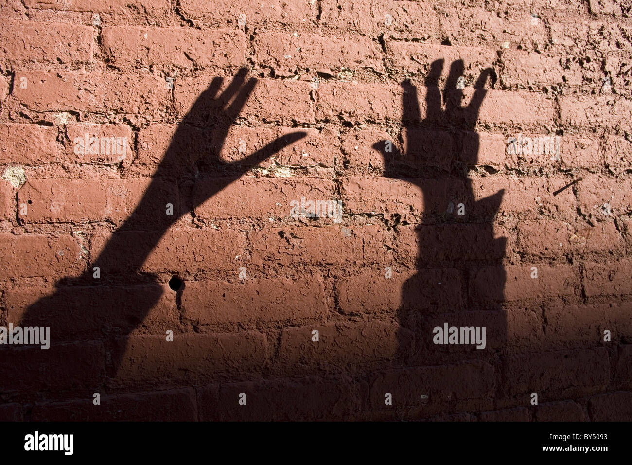 Expressive hand shadows on a brick wall. Stock Photo