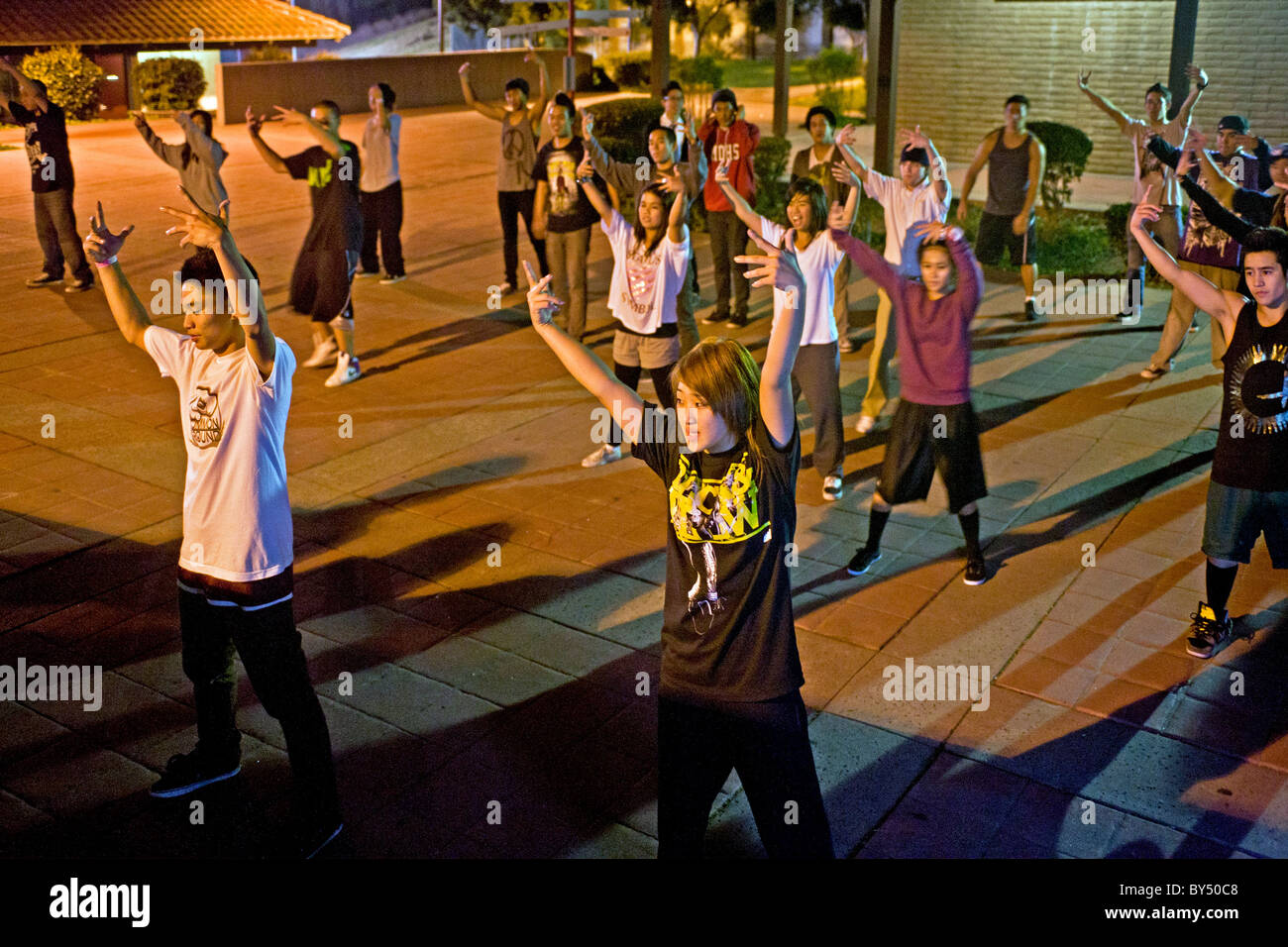 An Asian American college student conducts an informal night hip hop dancing class outdoors on campus in California. Stock Photo