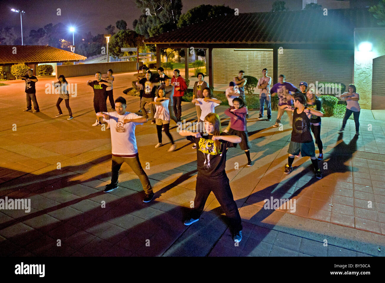 An Asian American college student conducts an informal night hip hop dancing class outdoors on campus in California. Stock Photo