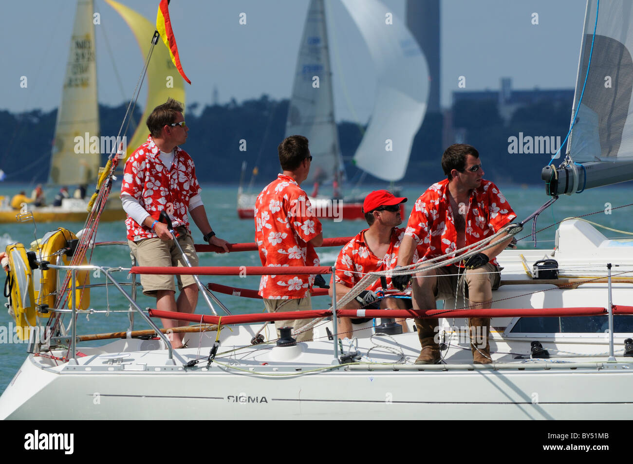 Boys in colourful  red shirts taking part in racing during Cowes Week, Isle of Wight, UK Stock Photo