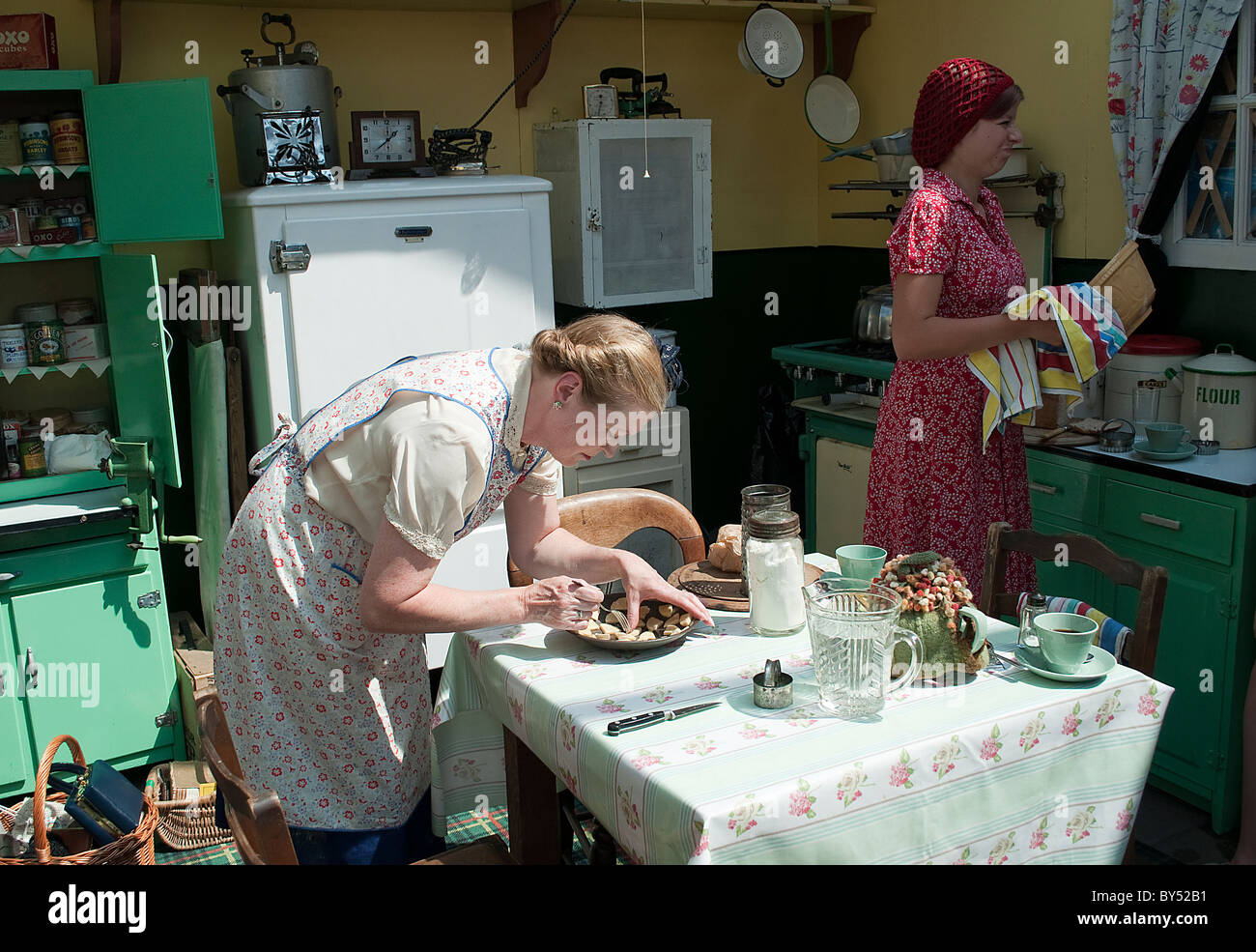 Ladies in 1940's style kitchen preparing cakes and washing up at the