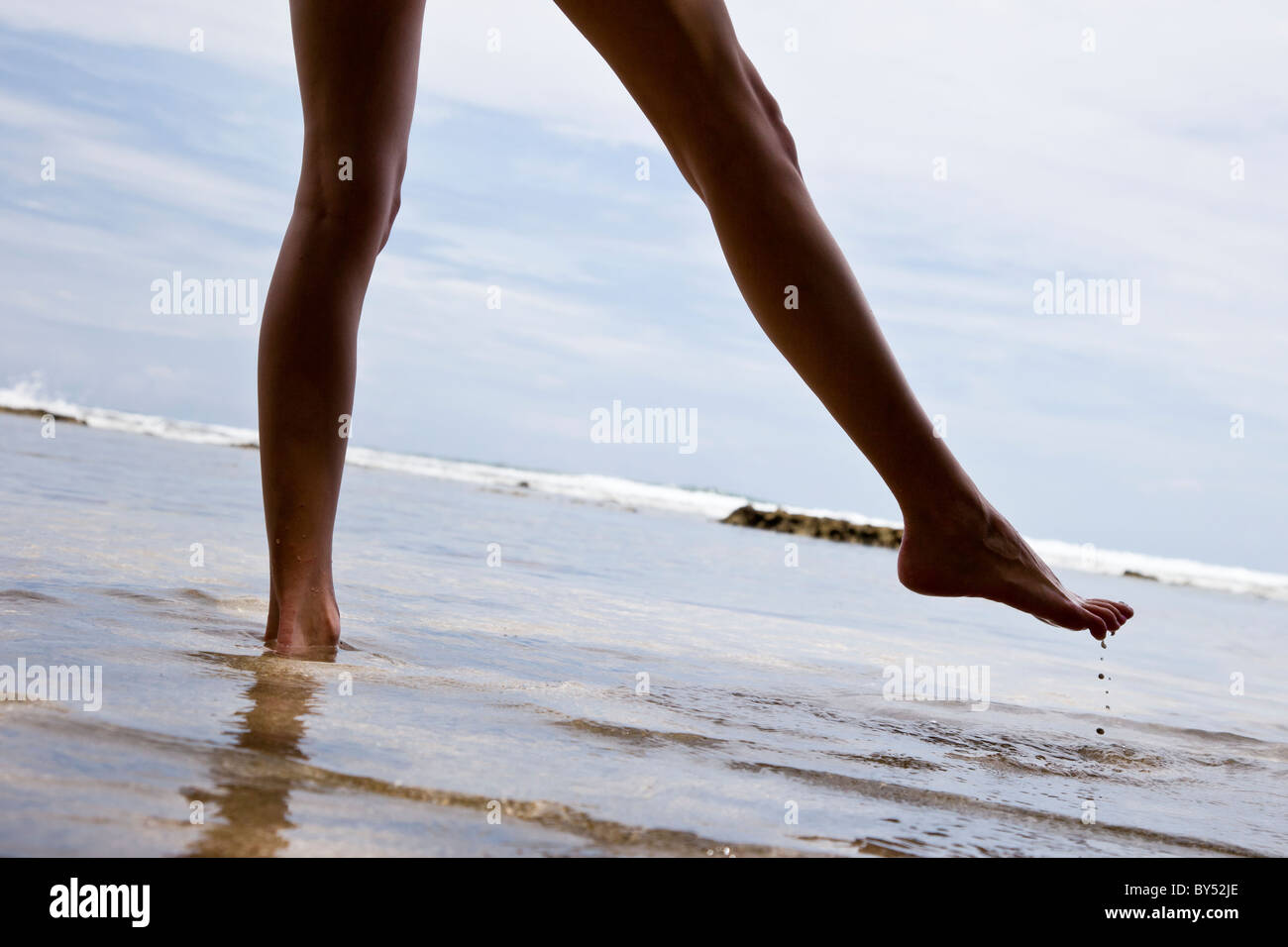 Woman dipping her feat in the sea along the coast of Puerto Viejo de Talamanca in Limon Province, Costa Rica. Stock Photo