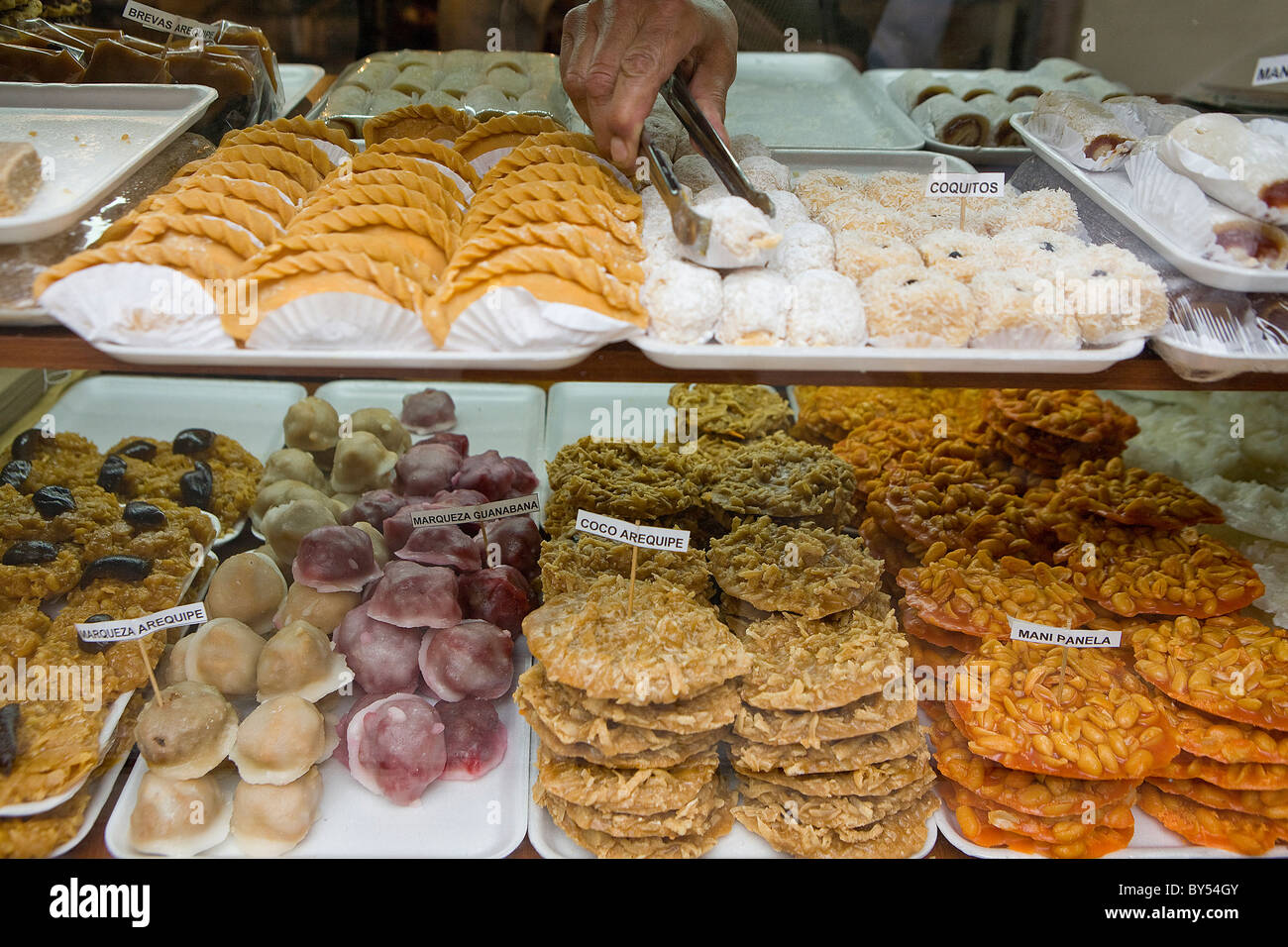 A Colombian man choosing dulces or sweets with tongs from a bakery window, Bogota, Colombia Stock Photo
