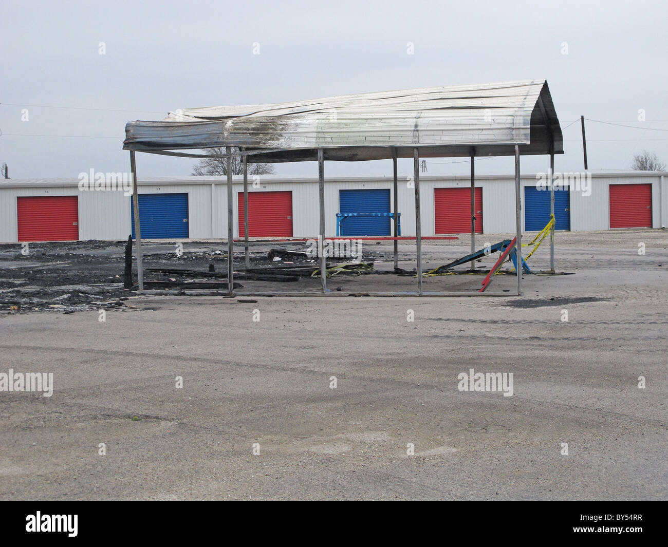 Burned building with a red and blue storage building Stock Photo