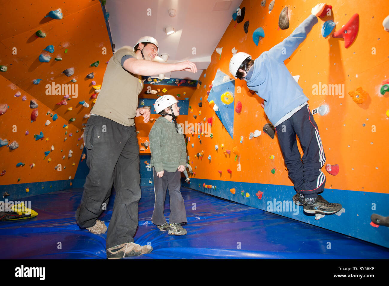 An instructor takes young children for a less on the bouldering section