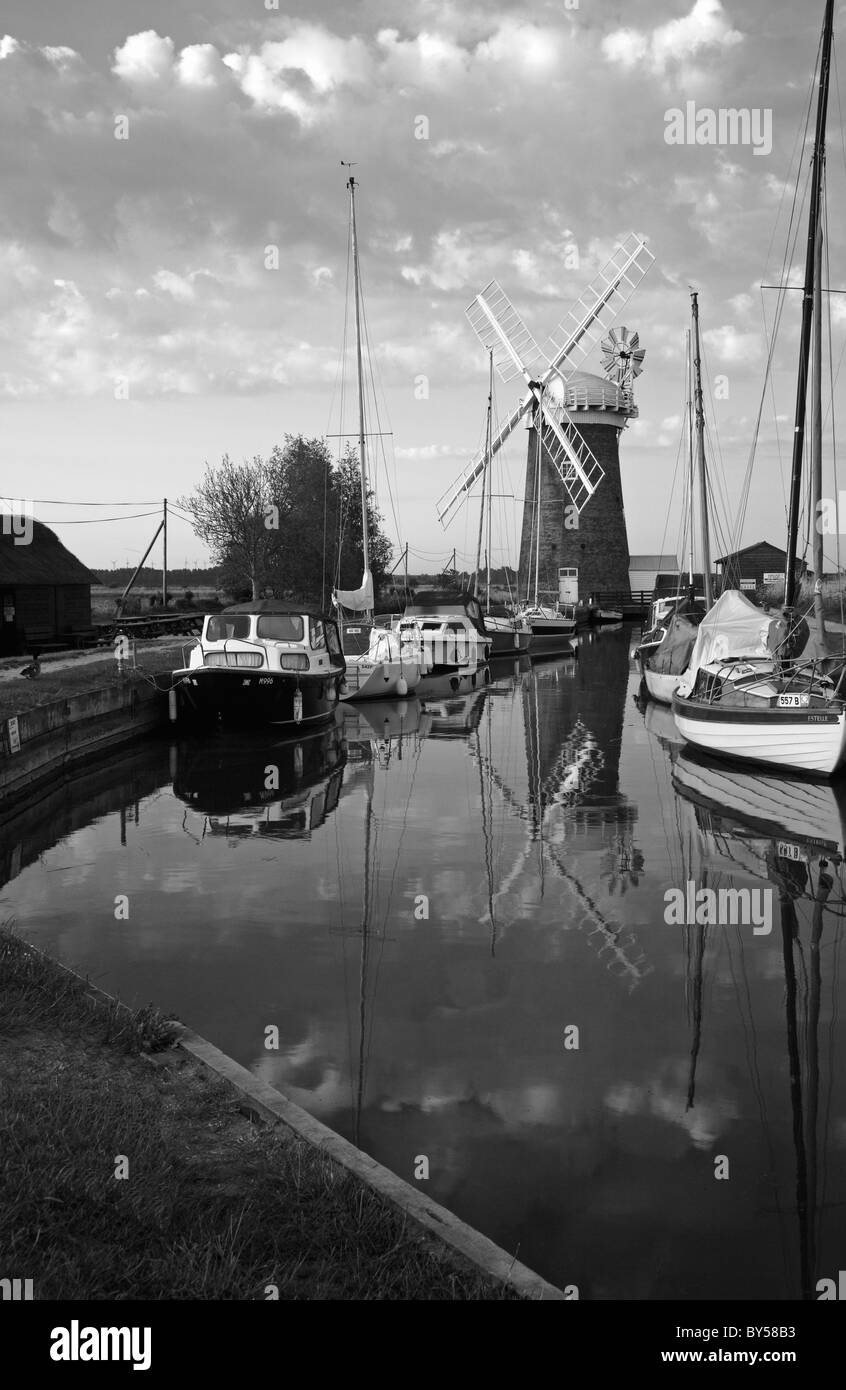 A black and white scene of Horsey Mill and boats moored in Horsey Dyke on the Norfolk Broads, England, United Kingdom. Stock Photo