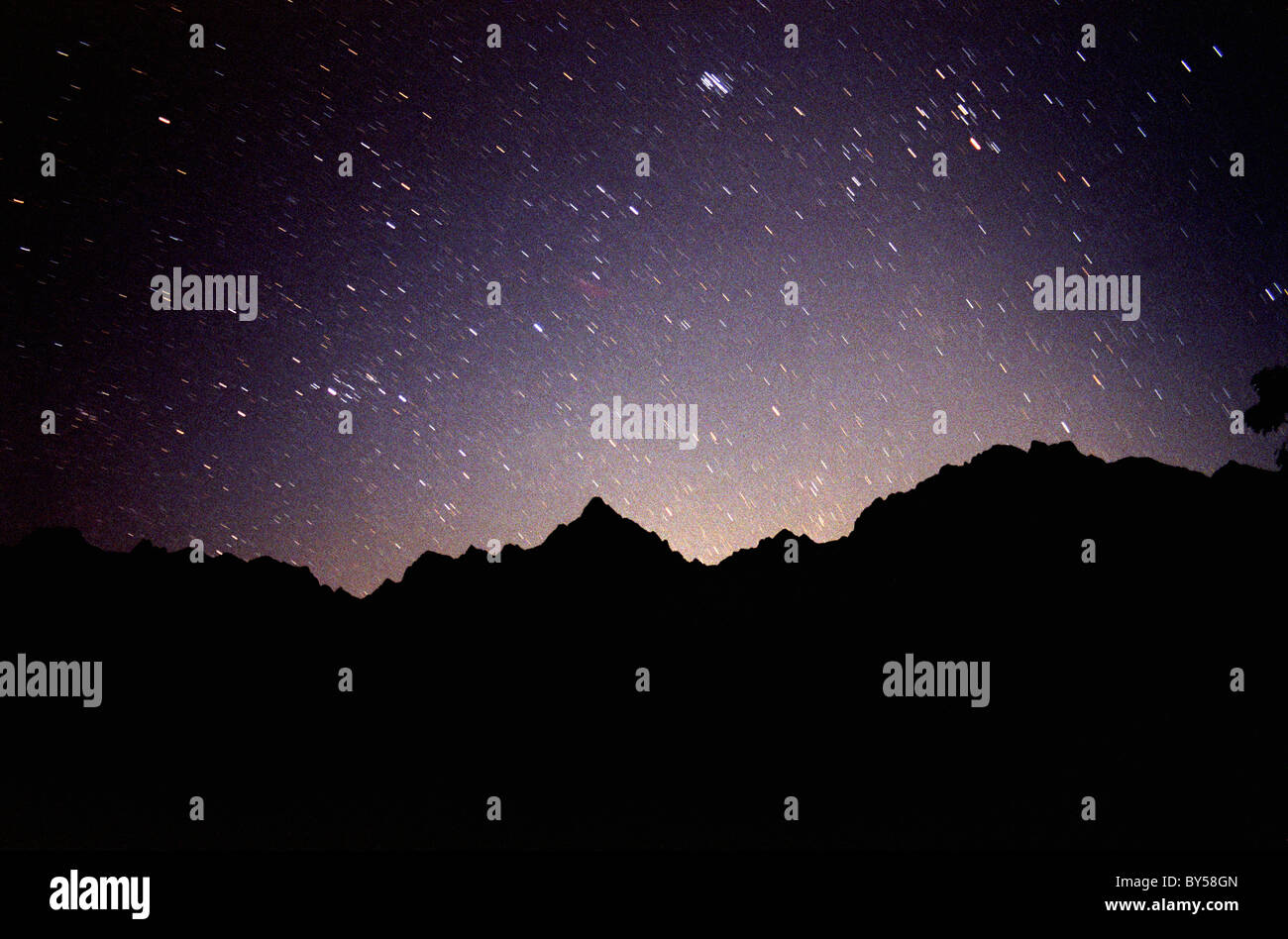 A mountain silhouetted against a night sky filled with stars Stock Photo