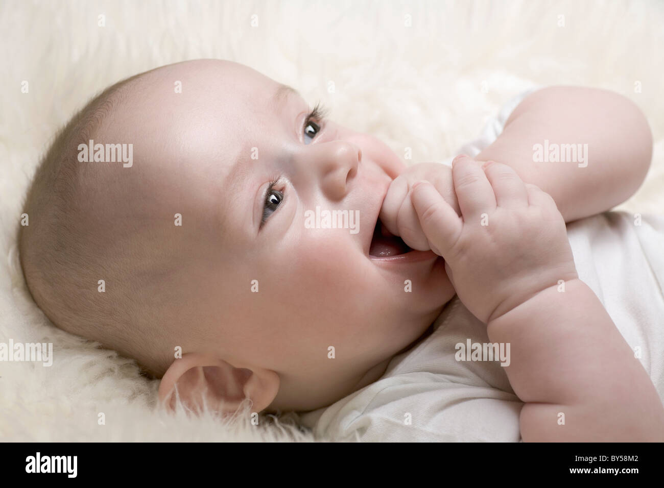 A cheerful baby with his hand in his mouth Stock Photo