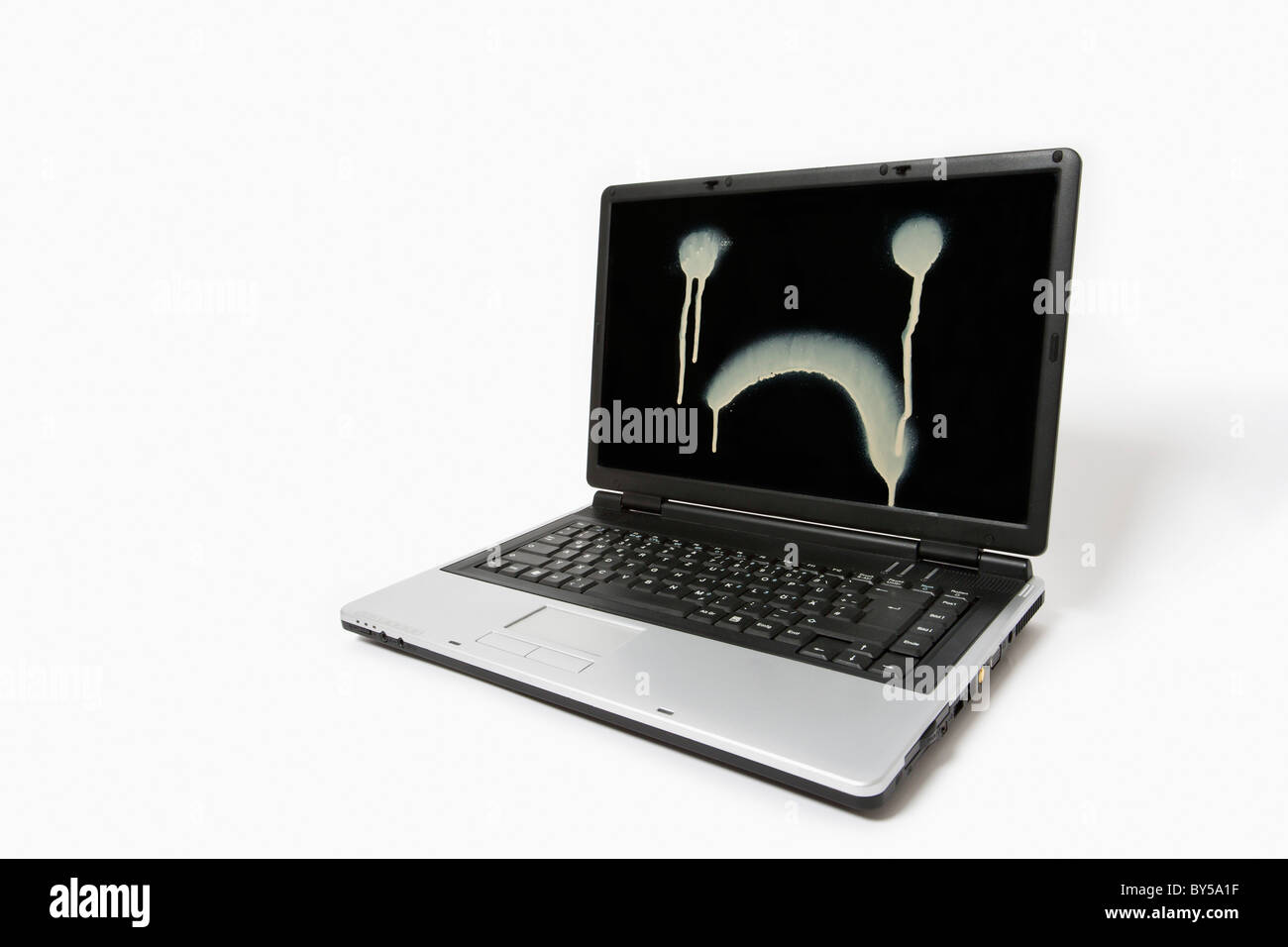 A laptop monitor with a sad face spray painted on it Stock Photo