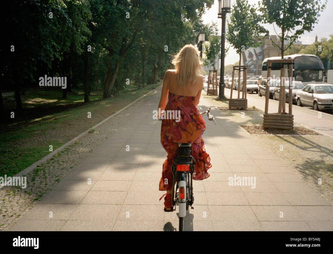 Rear view of a woman riding a bicycle on a footpath Stock Photo Alamy