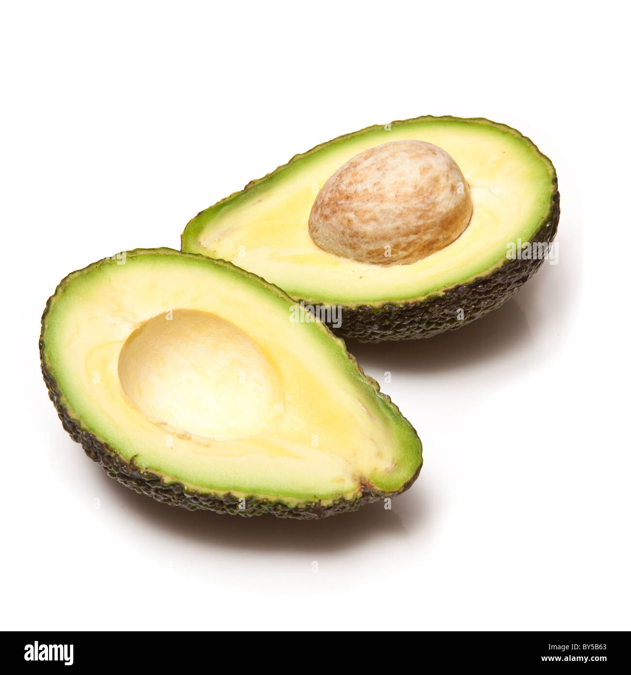 Avocado pear halved and isolated on a white studio background. Stock Photo