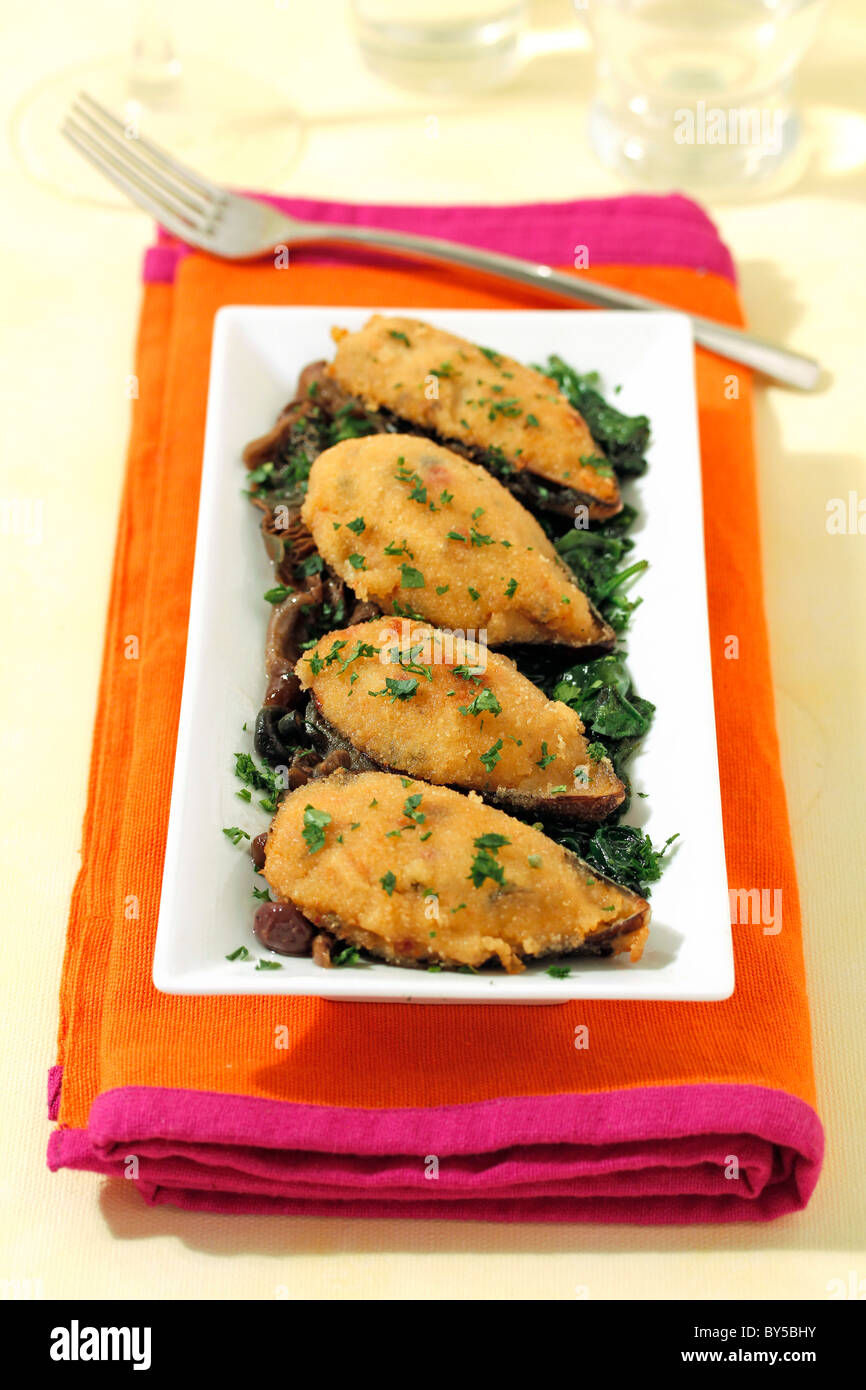 Stuffed mussels on spinach and mushrooms, Recipe available. Stock Photo