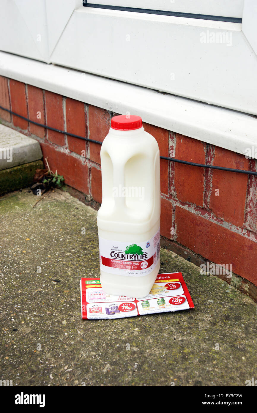 plastic bottle container of skimmed milk, doorstep delivery from the milkman with a promotional leaflet of offers Stock Photo