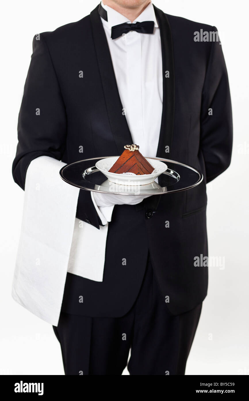 A butler holding a slice of a cake on a silver tray, midsection Stock Photo